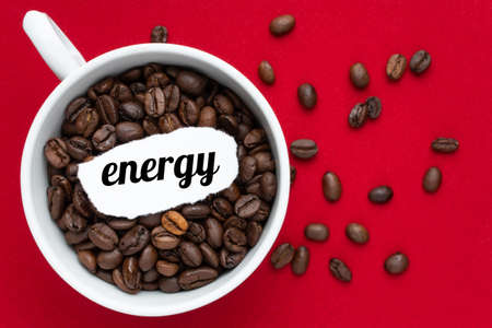 Text energy in a cup with coffee on a red background, coffee beans