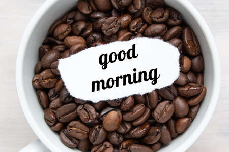 Text "good morning" in a cup with coffee on a light backgroundの写真素材