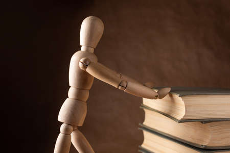 Wooden man moves book on brown backgroundの写真素材