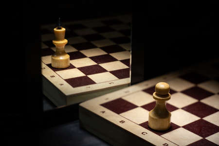 Chess piece pawn sees himself queen in reflectionの写真素材