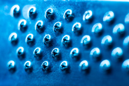 Metal surface with holes close-up in blue light, abstract background.の写真素材