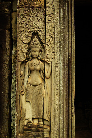 Graceful female figure carved in a stone-bas relief on an ancient Angkorian temple in Angkor Wat,...