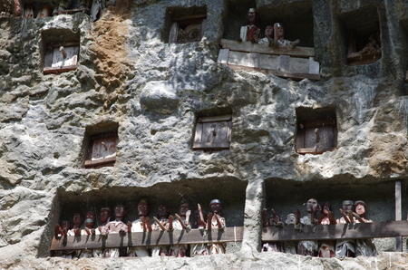 Graves watched by traditional guardians, spiritual wooden puppets watching  Tombs in the rock cliff  Toraja Highlands, Sulawesi, Indonesiaの写真素材