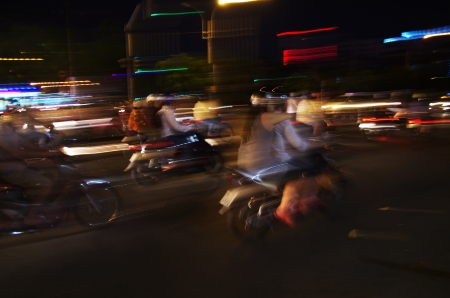 Motorbike drivers in a city, rushing by at night time, blurred lightsの写真素材