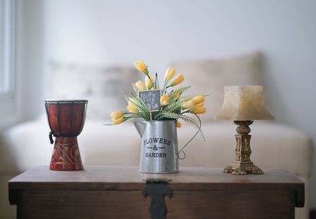 Vase with yellow and green flowers resting on a trunk, with a card that says happy dayの写真素材