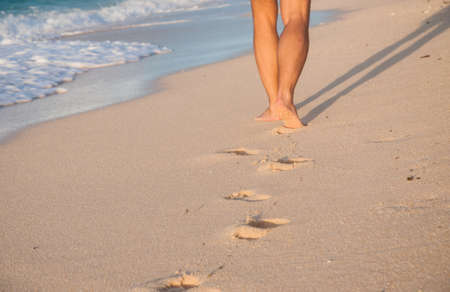 Closeup of a mans bare feet walking at a beach at sunset,の写真素材