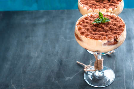 Tiramisu cake in a glass on a dark background decorated with mintの写真素材