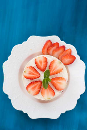 Summer strawberry mousse cake with fresh berries on the wooden blue background top viewの写真素材