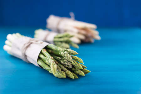 Bunch of fresh asparagus on blue wooden tableの写真素材