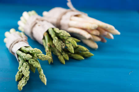 Bunch of fresh asparagus on blue wooden tableの写真素材
