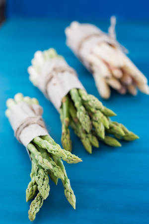 Bunch of fresh asparagus on blue wooden tableの写真素材