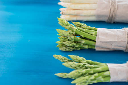 Bunches of green and white asparagus on a blue wooden background top viewの写真素材