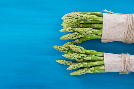 Bunches of green and white asparagus on a blue wooden background top viewの写真素材