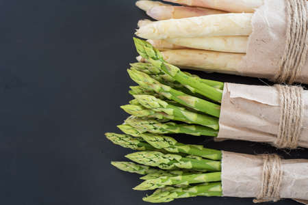 Bunches of green and white asparagus on a dark wooden background top viewの写真素材