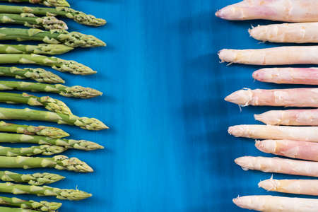 Fresh green, white asparagus shoots pattern, on a blue wooden background top viewの写真素材
