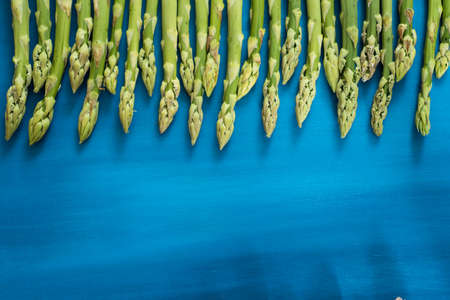 Fresh green asparagus shoots pattern, on a blue wooden background top viewの写真素材