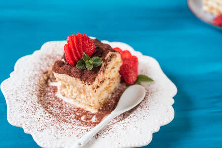 Piece of tiramisu cake with mint and strawberriesの写真素材