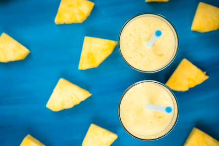 pineapple juice in a glass and pineapple fruits lying around top viewの写真素材