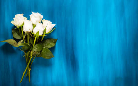 Valentines background. Floral bouquet made of white roses on blue background. Flat lay, top view. Valentines Day background.の写真素材