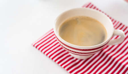 Red coffee cup over kitchen red strips towel. View from above. Isolated on white backgroundの写真素材