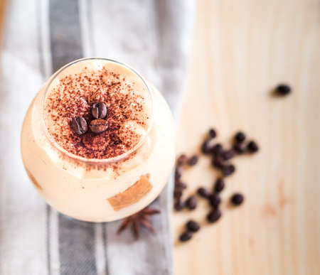 Tasty tiramisu dessert in glass, on napkin, on wooden backgroundの写真素材