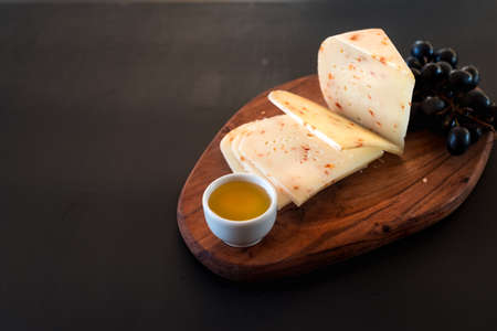 Cheese with red pepper, honey, grapes, cheese board, black, background Selective focus. Copy space.の写真素材
