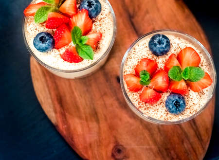 Homemade italian dessert tiramisu with strawberries, mint and blueberry in glass top viewの写真素材