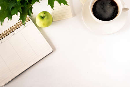 White designer office desk table with blank notebook page with cup of coffee and apple. Top view, flat lay.の写真素材