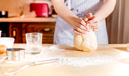 Womans hands knead dough on a table