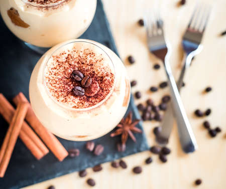 Tiramisu in a glass decorated with coffee beans on a dark background, concept of a sweet and luxurious lifeの写真素材