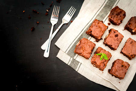 Homemade chocolate brownies on a wooden plate close-up, top view