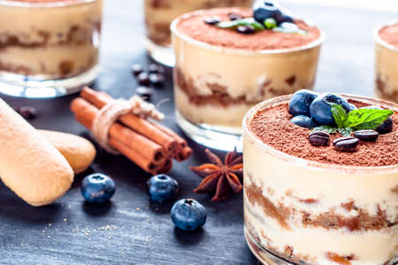 dessert tiramisu in glasses, decorated with blueberries and mint with coffee beansの写真素材