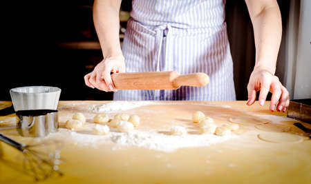 rolling out dough on kitchen table, close upの写真素材