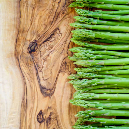 Asparagus, a bunch of fresh asparagus, on a wooden board of olive woodの写真素材