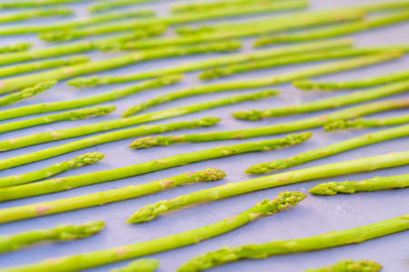 Fresh green asparagus shoots pattern, top view. Isolated over green. Food background asparagus patternの写真素材