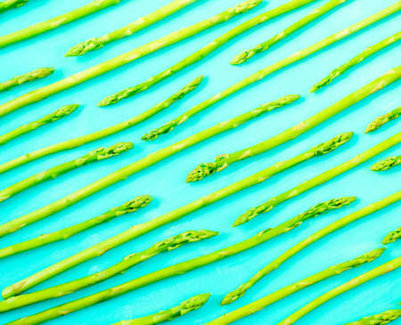 Fresh green asparagus shoots pattern, top view. Isolated over green. Food background asparagus patternの写真素材