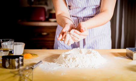 Making dough by female hands on kitchen table, close upの写真素材