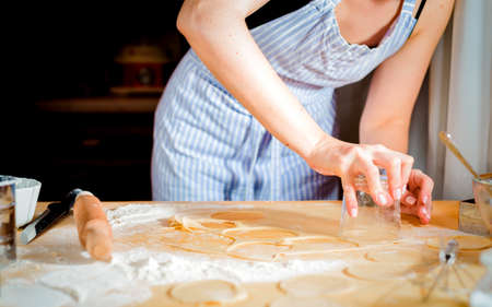 Female hands making dough on wooden tableの写真素材