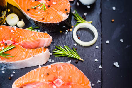salmon steak, pepper and salt, herbs on black stone concrete table, copy space top viewの写真素材