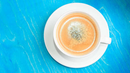 Cup of fresh coffee on blue wooden background, top view