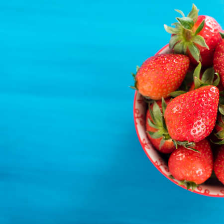 fresh bright strawberries in a bowl top view on blue backgroundの写真素材