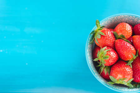 fresh bright strawberries in a bowl top view on blue backgroundの写真素材