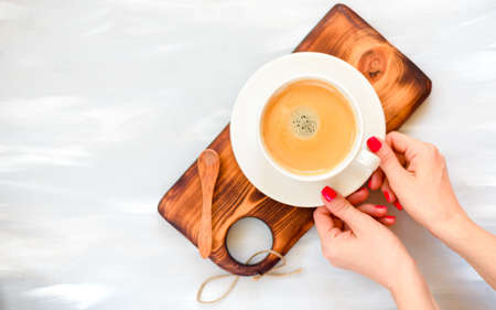 girls hands with red manicure holding coffee cup, flat lay, top viewの写真素材