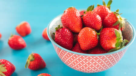 Bright print bowl of fresh strawberries on blue woodenの写真素材