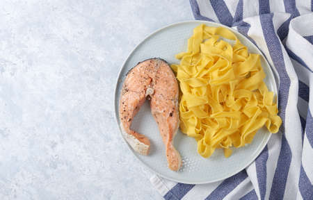 Italian pasta and steamed salmon in a blue plate.