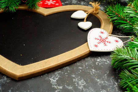 Christmas or New Year dark wooden background, Black board framed with season decorations, space for...