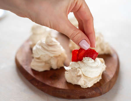 the process of creating Pavlova dessert, decorating the meringue with strawberriesの写真素材