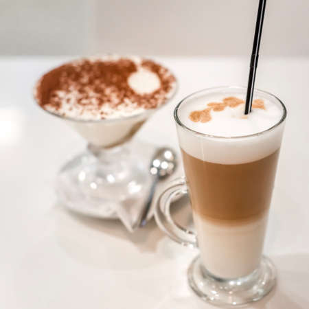 coffee latte with frothy milk in tall glass, rustic style, white woodの写真素材