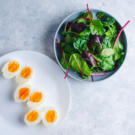 green salad with egg in a blue bowl on a blue backgroundの写真素材