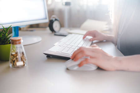girl typing on a white keyboard and uses mouseの写真素材